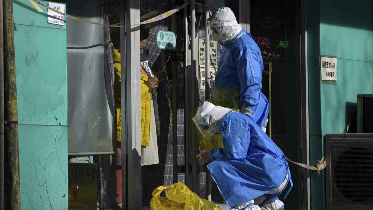 Workers collect a sample from a woman in a locked down Beijing store (AAP).jpg