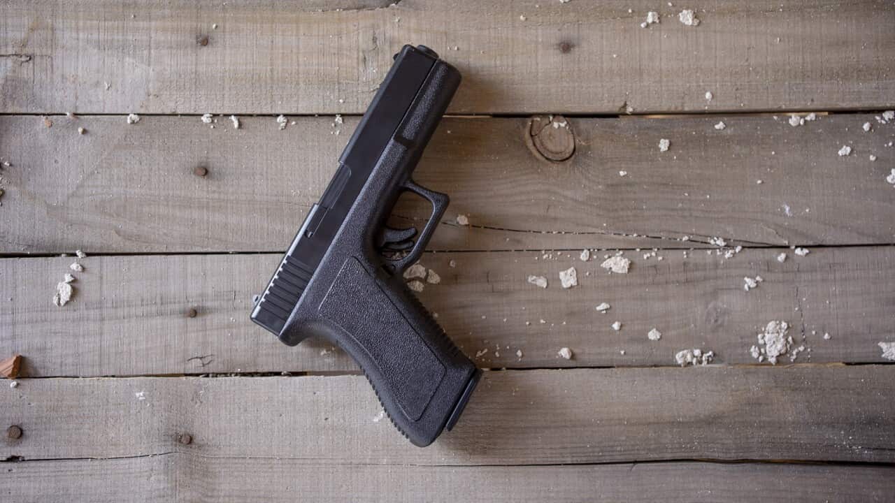 Top view of a gun on a rustic wooden surface