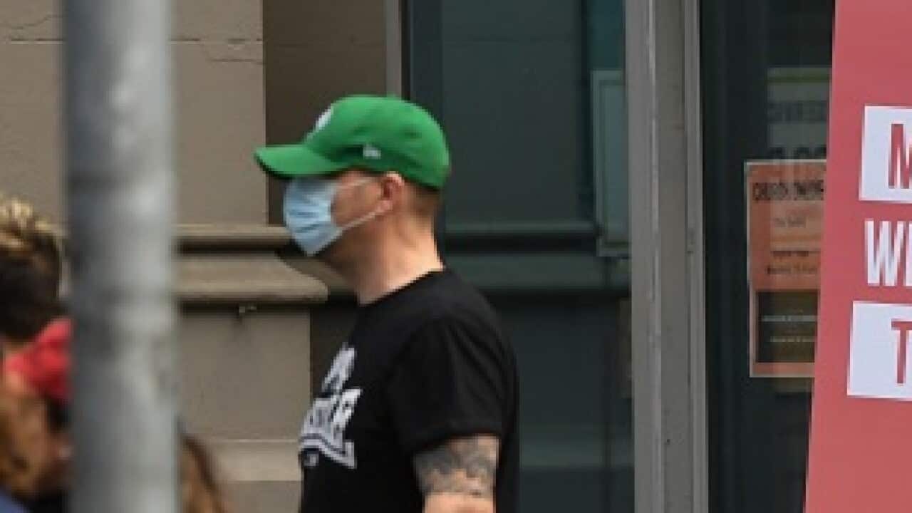 Protesters walk past a sign during an anti-lockdown protest in Melbourne, Sunday, September 13, 2020.