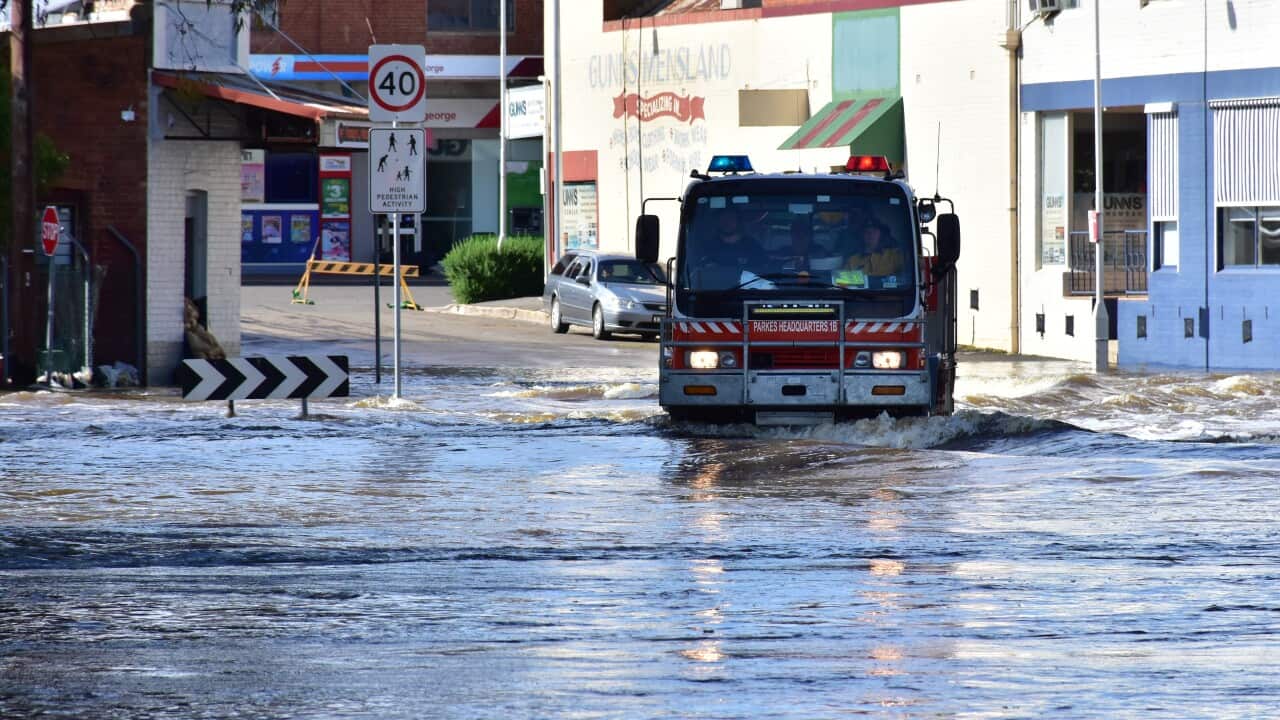 Emergency service vehicle driving through flooded street.