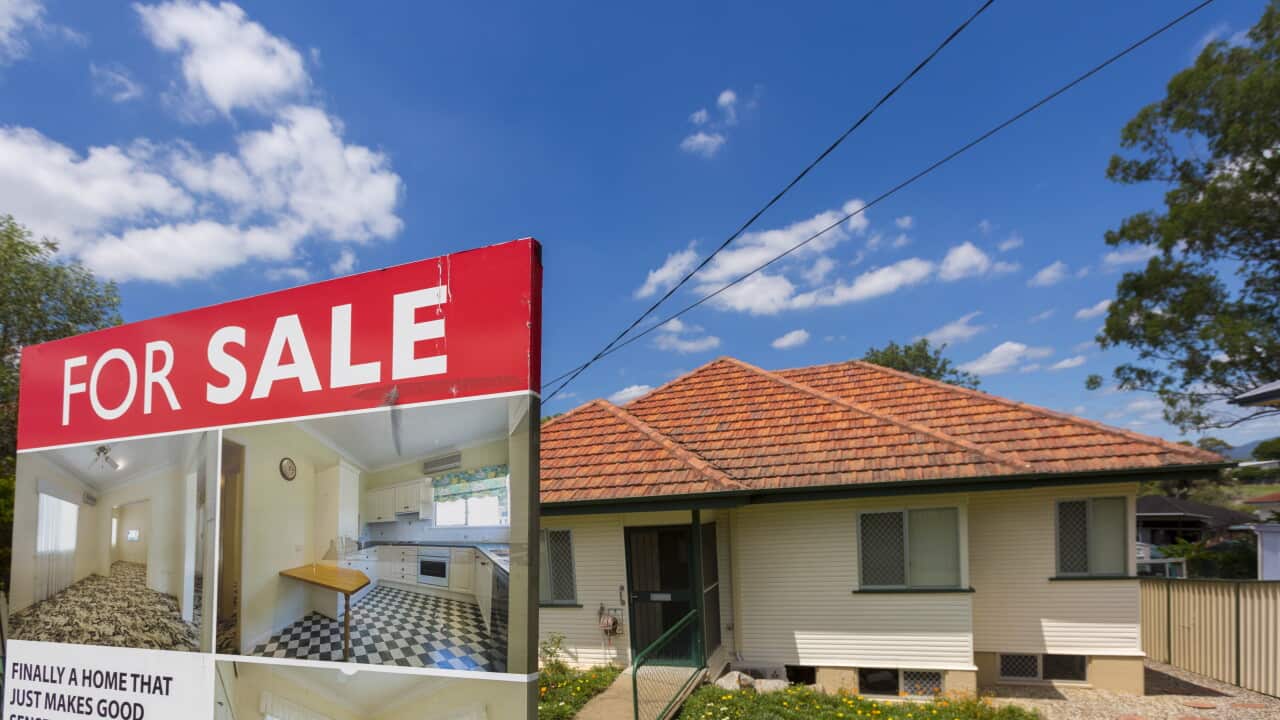 A suburban house with a 'FOR SALE' sign in front of it.