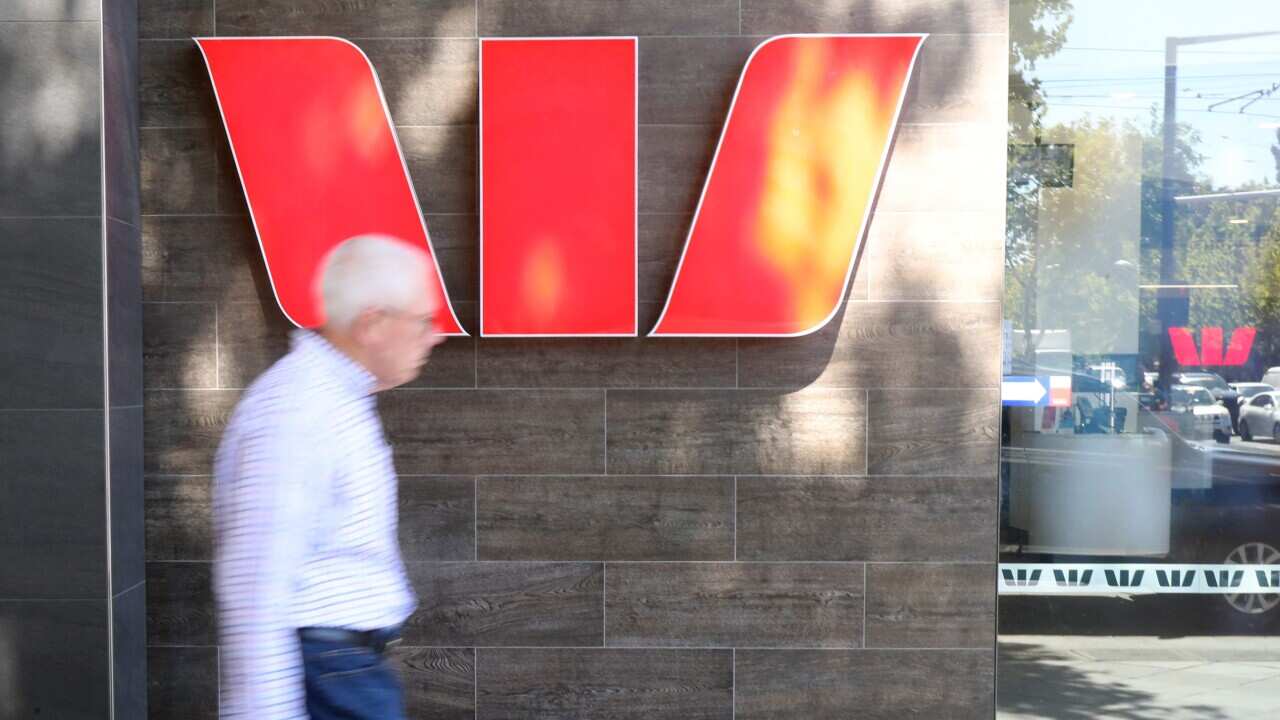 People walking past a Westpac sign