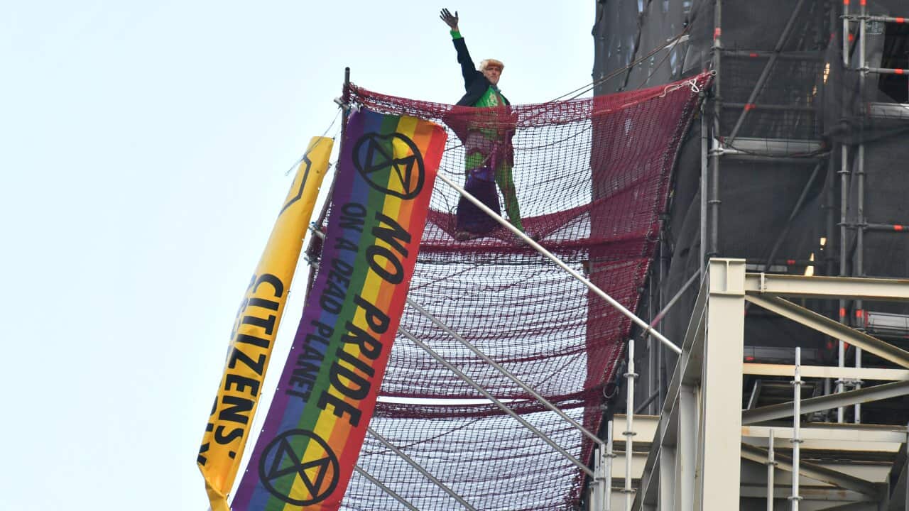 An Extinction Rebellion protester waves after scaling the scaffolding surrounding Big Ben at the Houses of Parliament, Westminster, London.