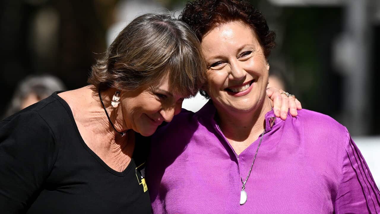 A woman with her arm around the shoulders of another woman who is smiling.
