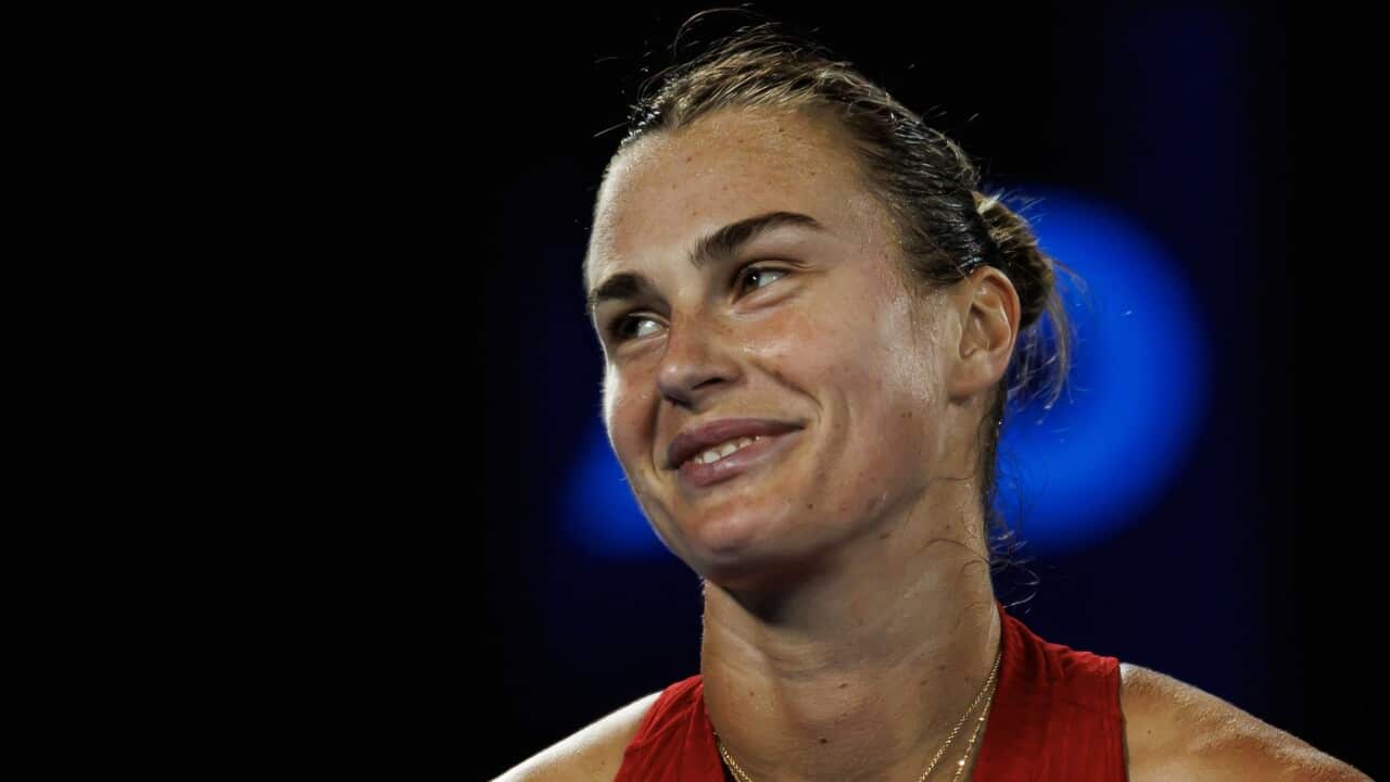 Aryna Sabalenka smiling in front of a black background with the Australian Open logo.