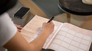 A person holding a pen fills out a paper document
