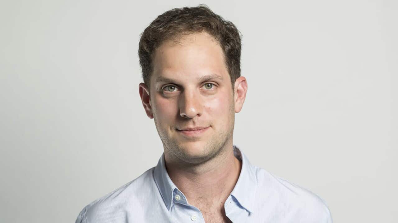 American journalist Evan Gershkovich wears a light blue collared shirt and looks straight to camera.