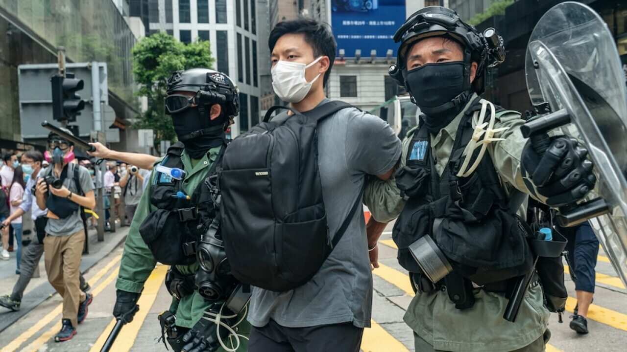 A pedestrian is detained by riot police in Hong Kong on Wednesday.
