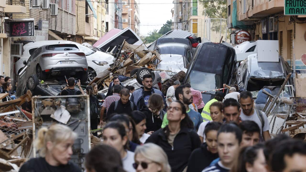 People walking in front of piled-up cars
