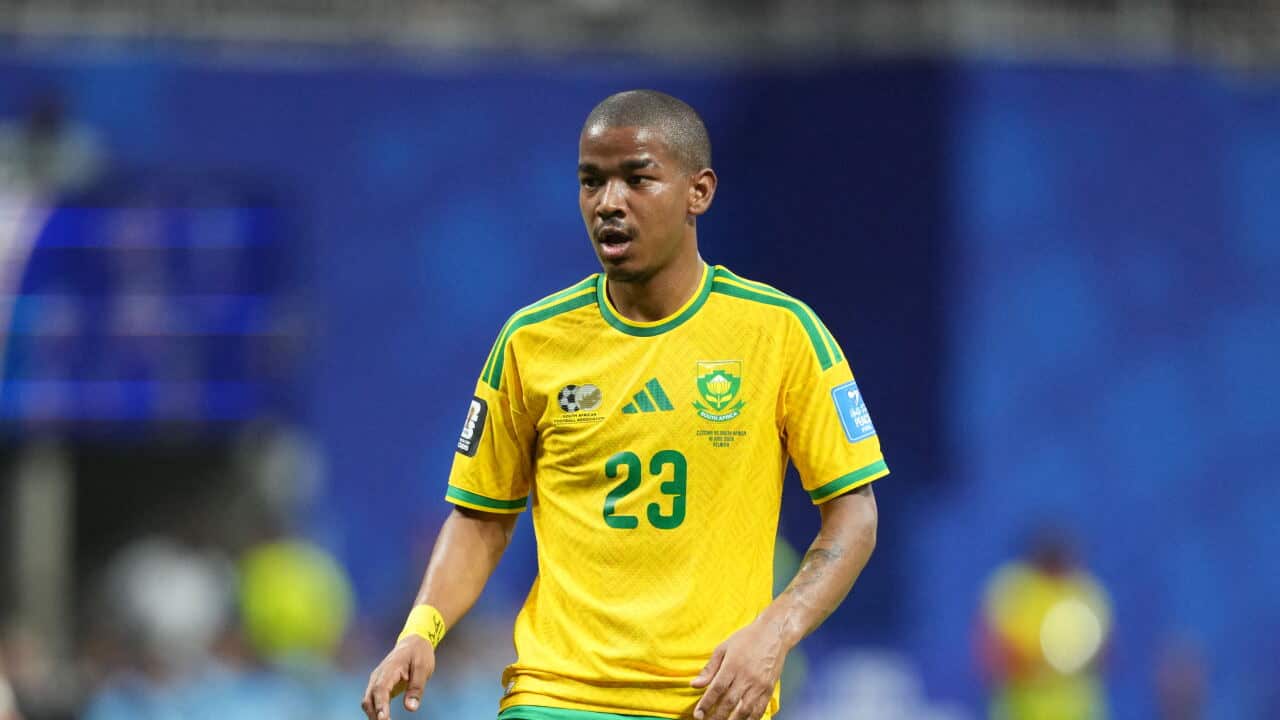 A football player in a yellow and green jersey looks on