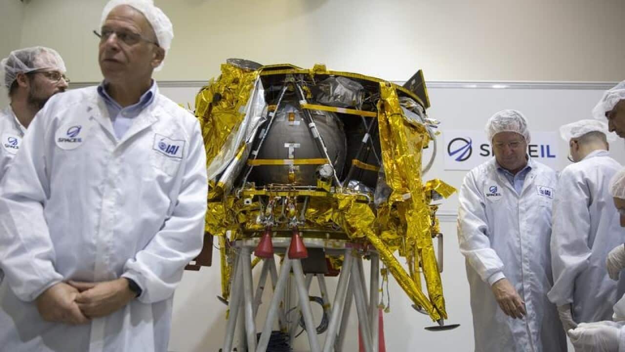 technicians stand next to the SpaceIL lunar module