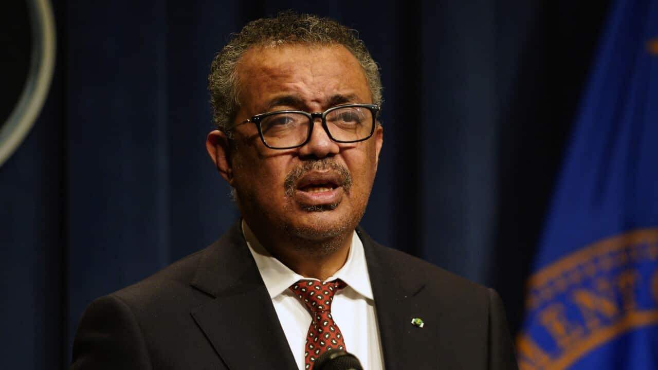 A man wearing a black suit is speaking.