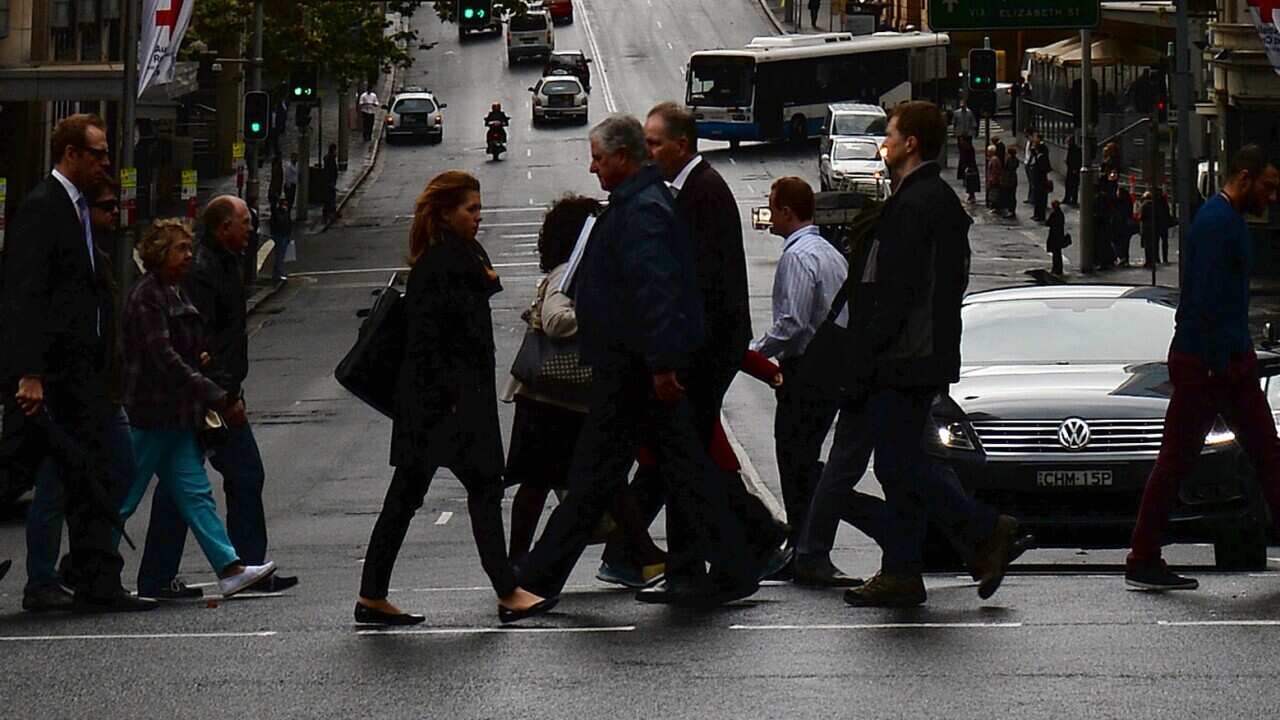 Office employees cross a road in the central business district of Sydney on June 19, 2013. (SAEED KHAN/AFP/Getty Images)