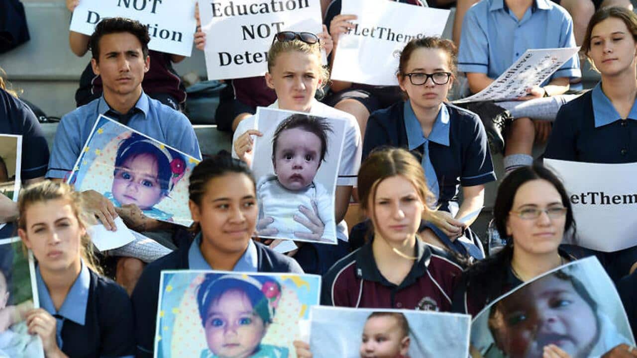 School students hold photos of a baby girl known as Asha during a protest outside the Lady Cilento Children's Hospital in Brisbane, Thursday, Feb. 18, 2016. (AAP)