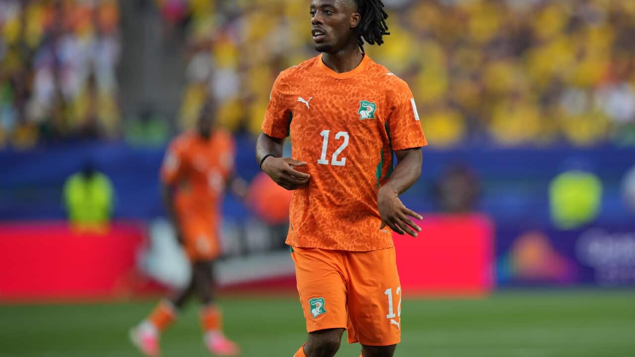A male football player in an orange uniform on the pitch.