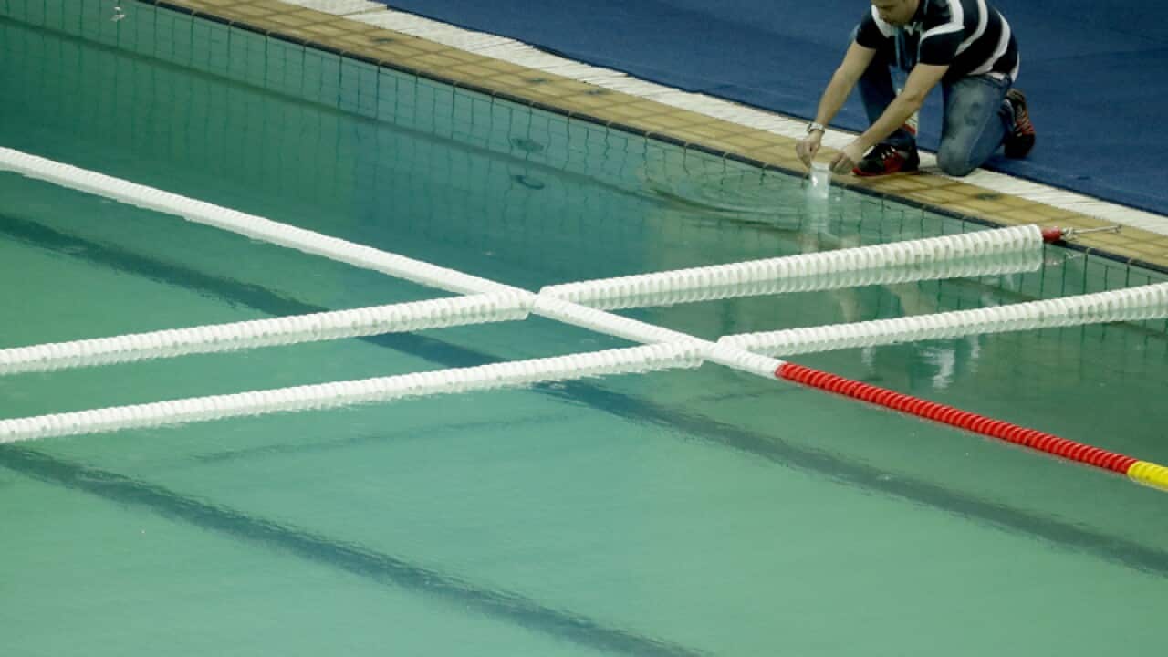 An inspector takes a sample from the water polo pool