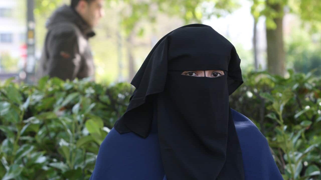 (File Image) A woman wears the niqab as she sits in a park in Brussels in 2010.