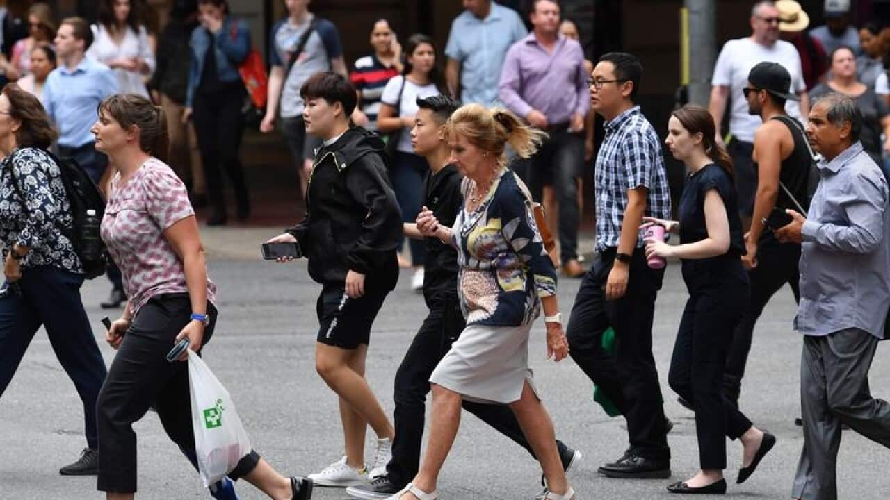 Pedestrians cross an intersection in the Brisbane CBD