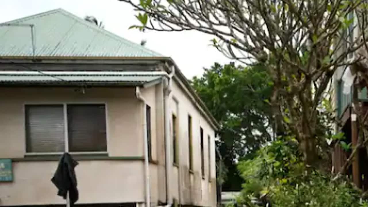 A rural fire service volunteer inspects a house surrounded by floodwater on 31 March, 2022 in Lismore, NSW.