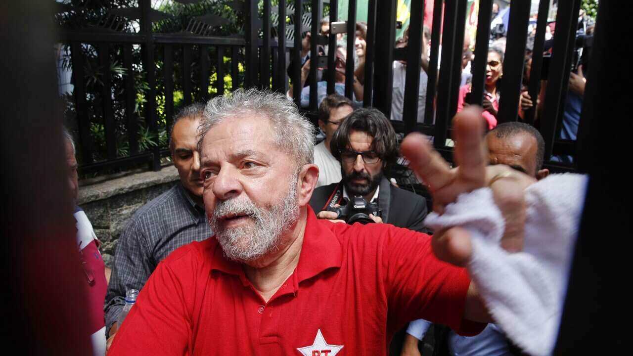 Brazil's former President Luiz Inacio Lula da Silva greets supporters who have gathered outside his residence, in Sao Bernardo do Campo