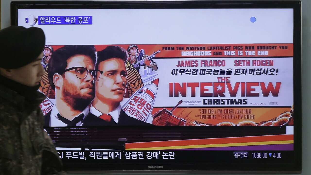 A South Korean army soldier walks near a TV screen showing an advertisement of Sony Picture's "The Interview," at the Seoul Railway Station in Seoul (AAP)