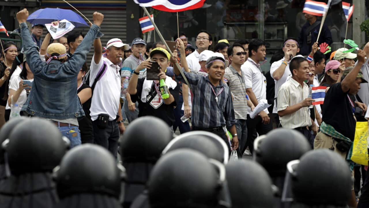 Anti-government protesters march in front of anti-riot police
