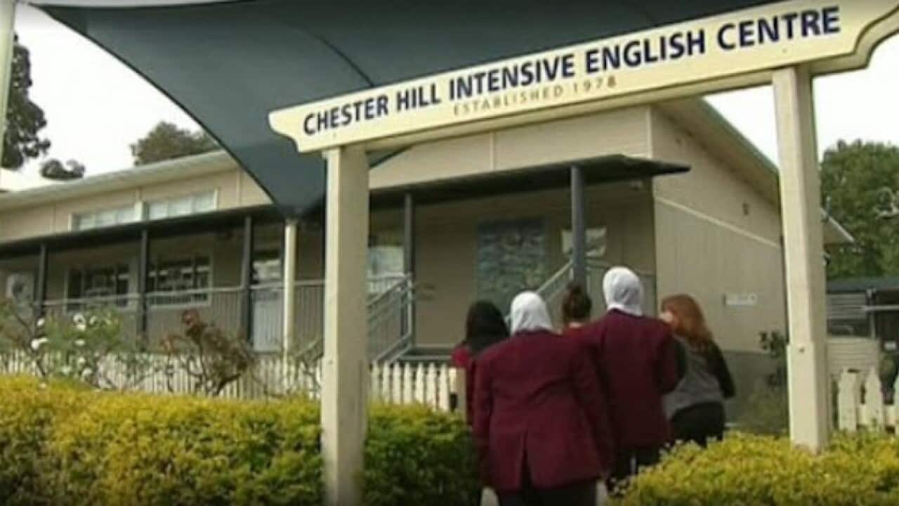 Rear view of students walking under a sign outside that reads: Chester Hill Intensive English Centre