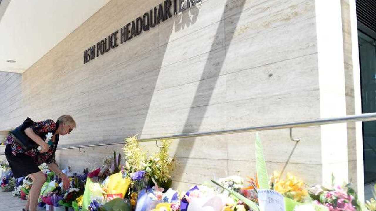 A women looks at flowers placed for police employee Curtis Cheng outside of the NSW Police Headquarters in Sydney