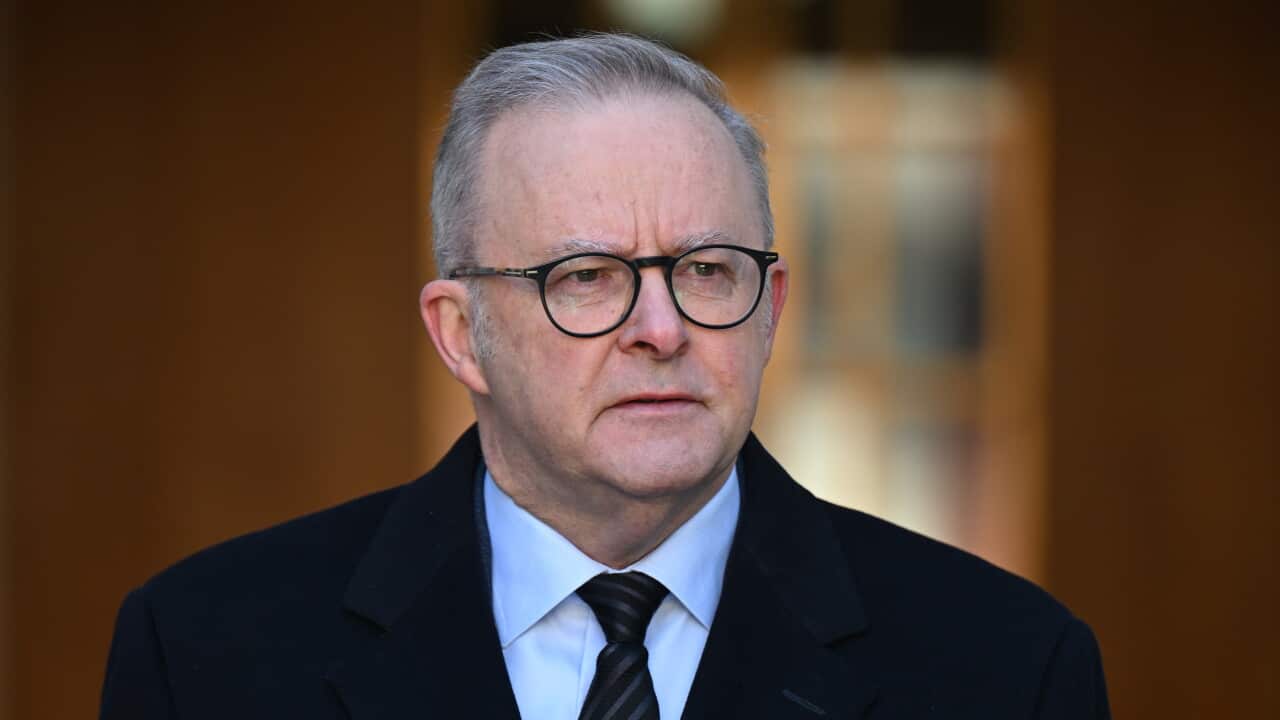 A man wearing a black coat and glasses