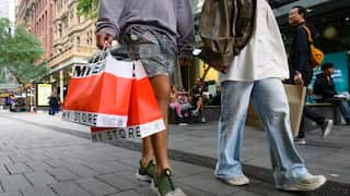 Shoppers walking through a busy urban shopping district.
