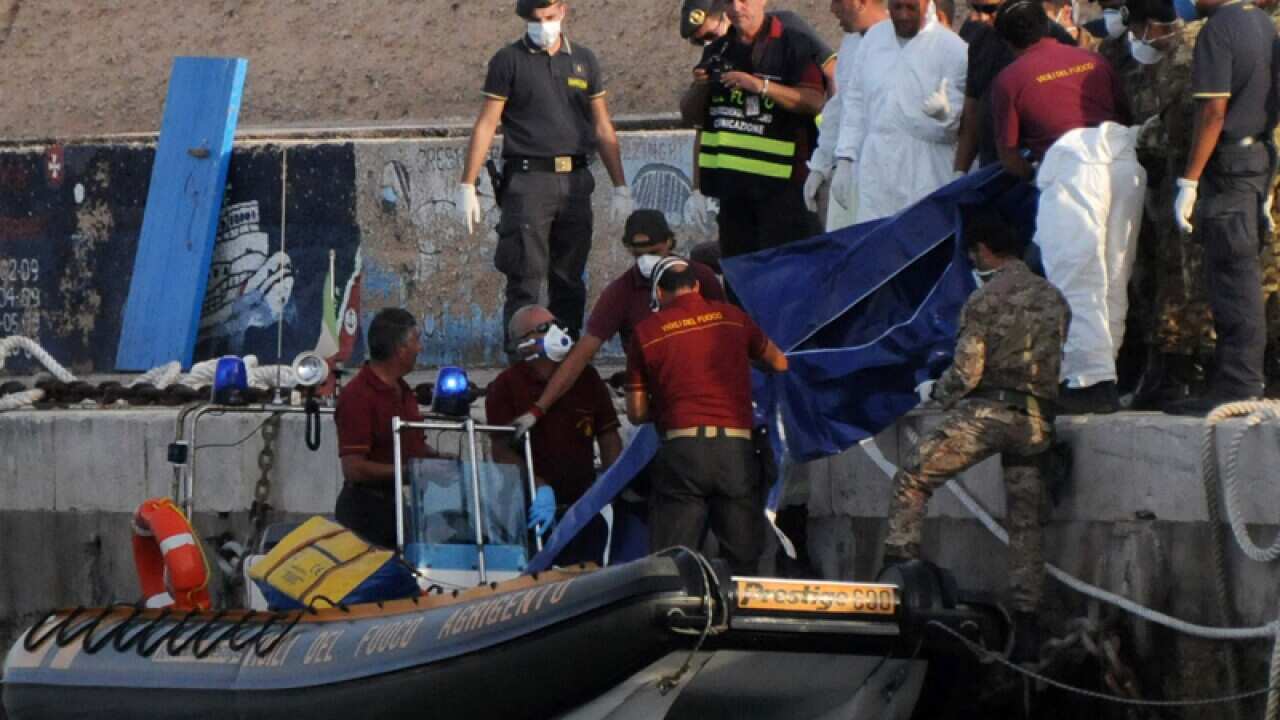 Rescuers lift a body bag as they reach the port of Lampedusa