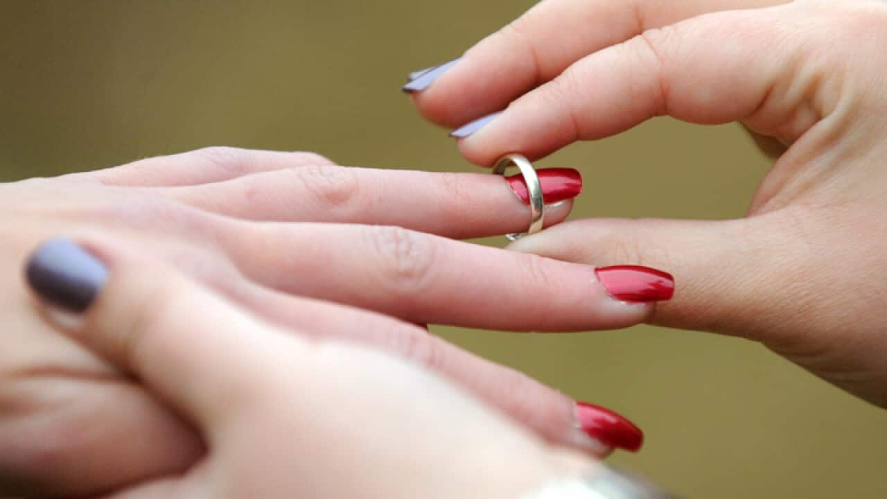 A woman places a wedding ring on her partners finger in Canberra