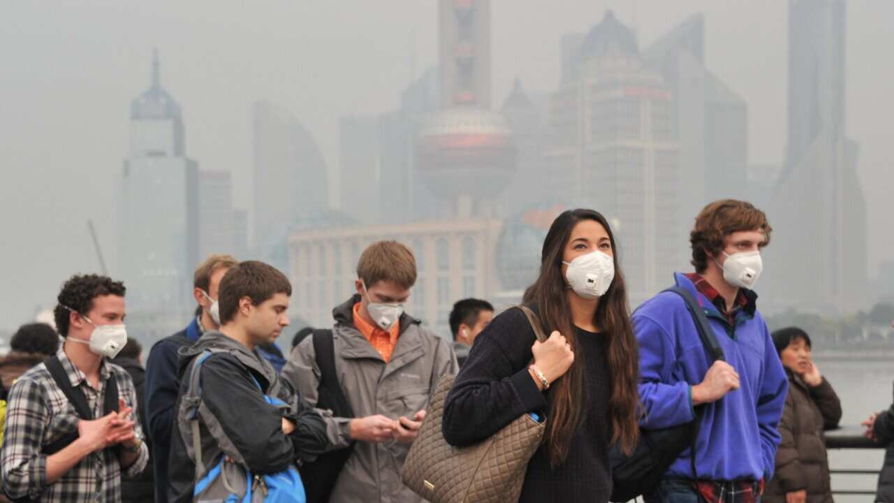 Foreign tourists wearing face masks against air pollution visit the promenade on the Bund in heavy smog in Shanghai, China, 3 January 2016.