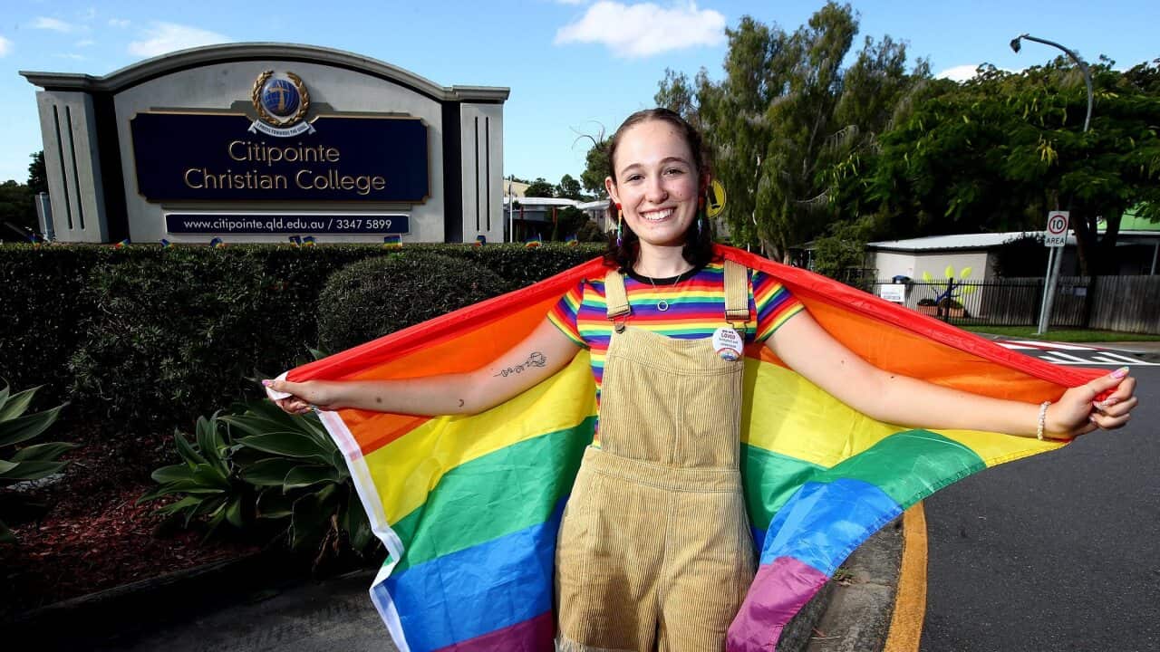 Former Citipointe Christian College student Felicity Myers poses with a pride flag outside the school.