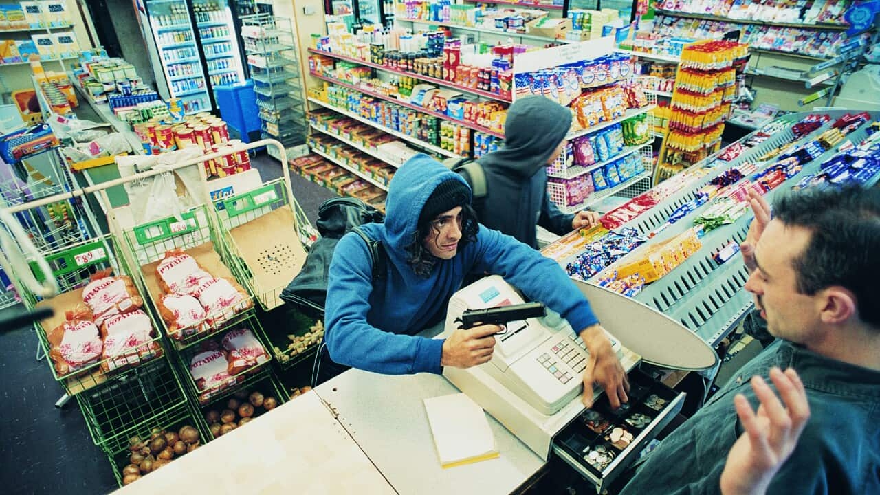 High Angle View of Two Robbers Robbing a Cash Till and Threatening a Shop Assistant with a Gun