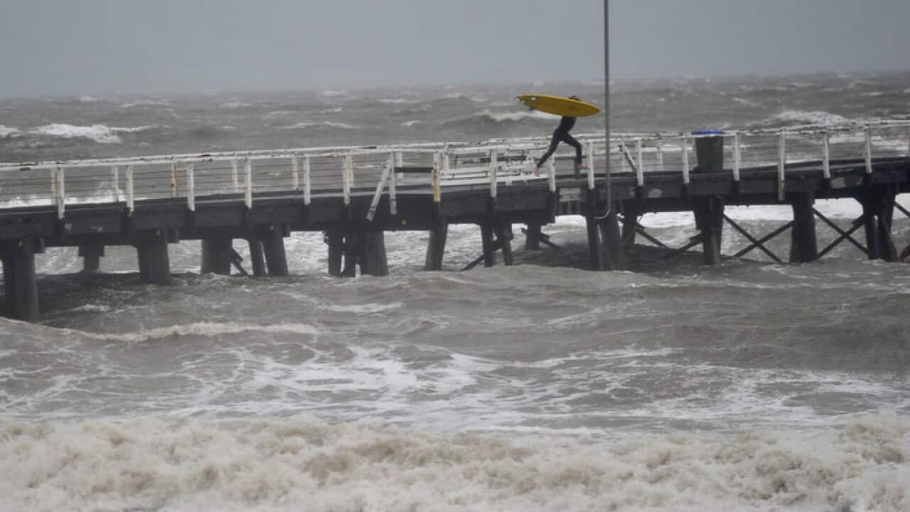 A surfer on a jetty jumps into the waves that have been created by a storm front on Adelaide metropolitan beaches, South Australia on Thursday Sept 29, 2016. (AAP Image/David Mariuz) NO ARCHIVING