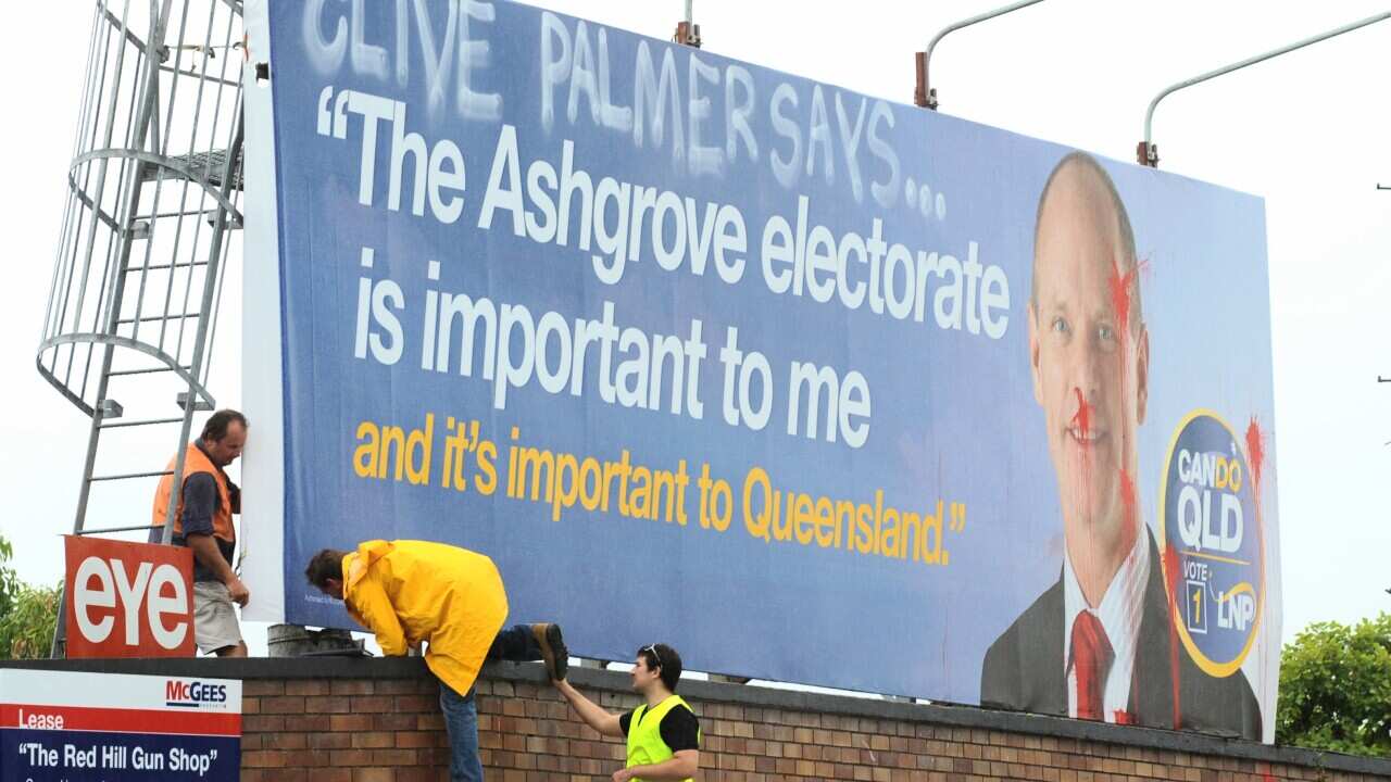 Workers inspect a defaced Liberal National Party (LNP) campaign billboard on a road leading into the Ashgrove electorate in Brisbane, Thursday, March 22, 2012. (AAP Image/Dave Hunt)