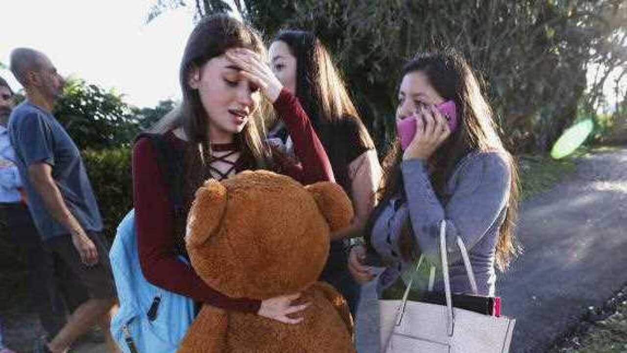 Students wait to be picked up after a shooting at Marjory Stoneman Douglas High School in Parkland, Fla.