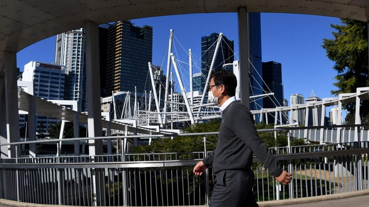 A man walks across the Kurilpa Bridge in Brisbane