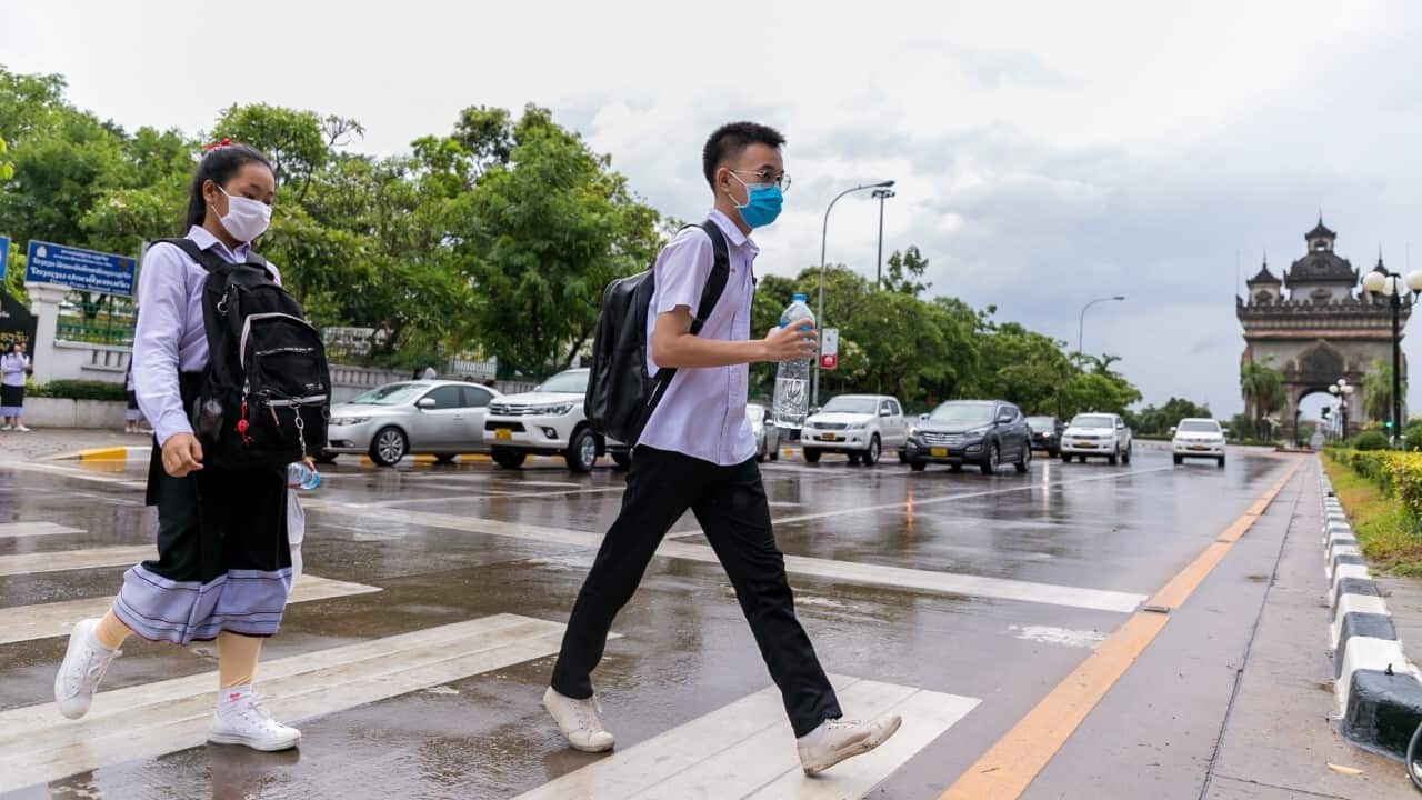 Students wearing masks cross a street after school in Vientiane, Laos, May 19, 2020 (Kaikeo Saiyasane - Xinhua via Getty)