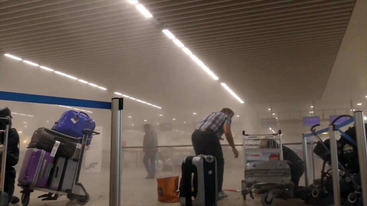 An unidentified traveller gets to his feet in a smoke filled terminal at Brussels Airport, in Brussels after explosions Tuesday, March 22, 2016.