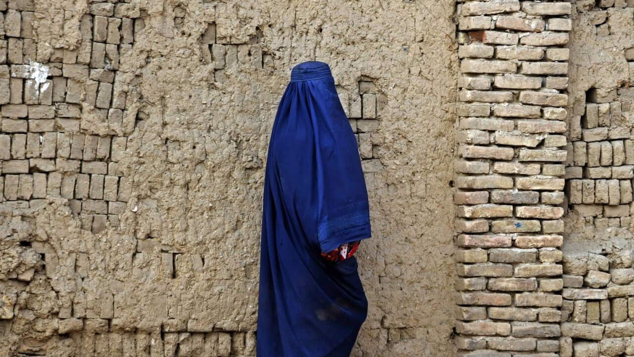 An Afghan woman walks through a street in Kandahar