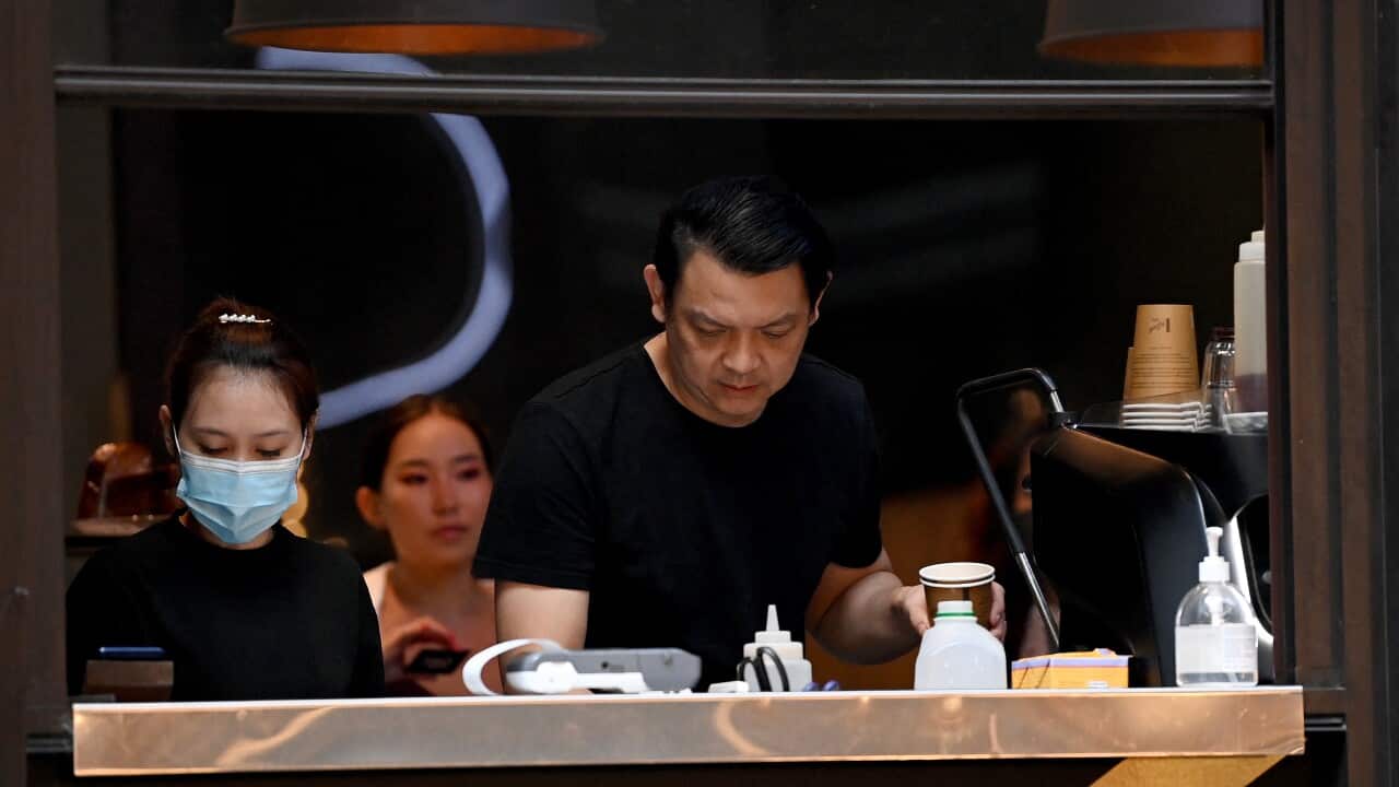 A man and a woman are making coffee in a cafe.
