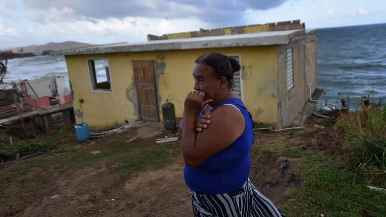 Maria Martinez stands next to her house which was damaged by Hurricane Maria in Puerto Rico