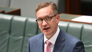 A man in a suit speaking in parliament.