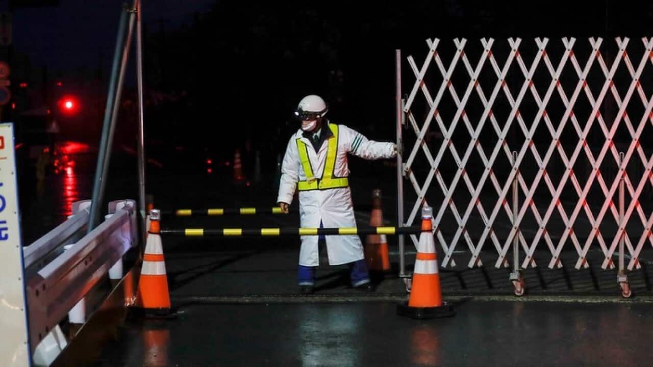 A security staff closes a street at a checkpoint to central Futaba town