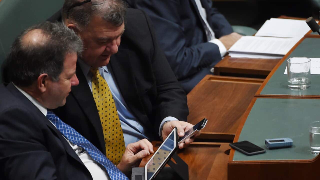 Federal member for Hughes Craig Kelly (2nd from left) shares something on his phone with Member for Tangney Dennis Jensen during Question Time at Parliament House in Canberra, Wednesday, Oct. 14, 2015. (AAP Image/Dean Lewins) NO ARCHIVING