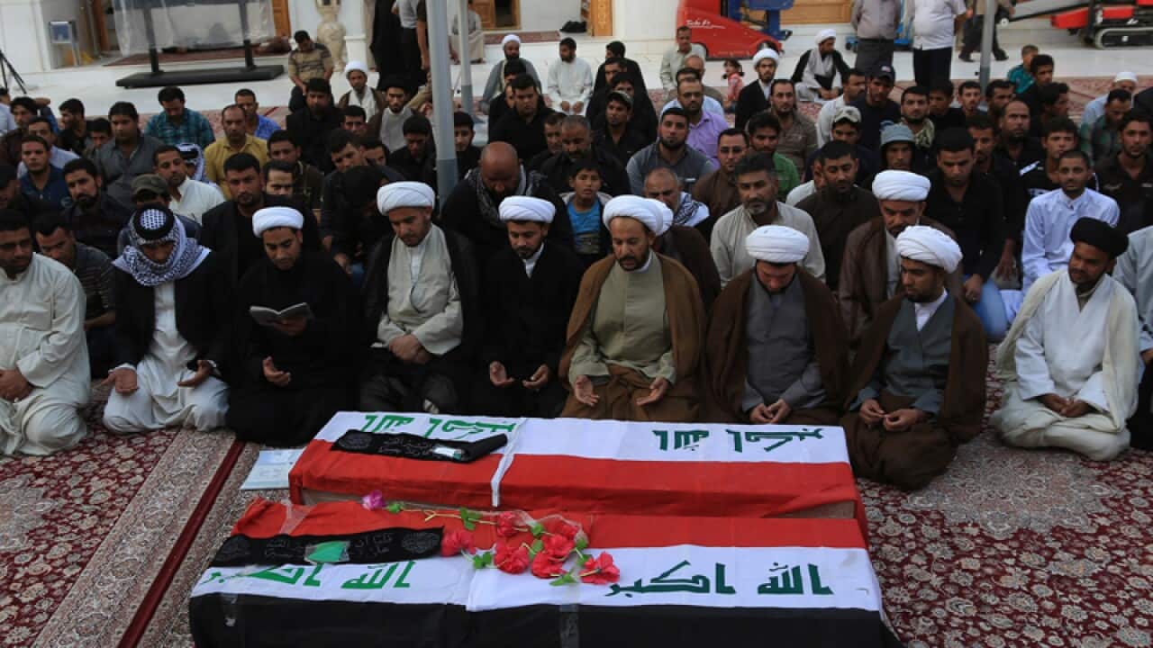 Mourners pray over the coffins of two Shi'ite fighters