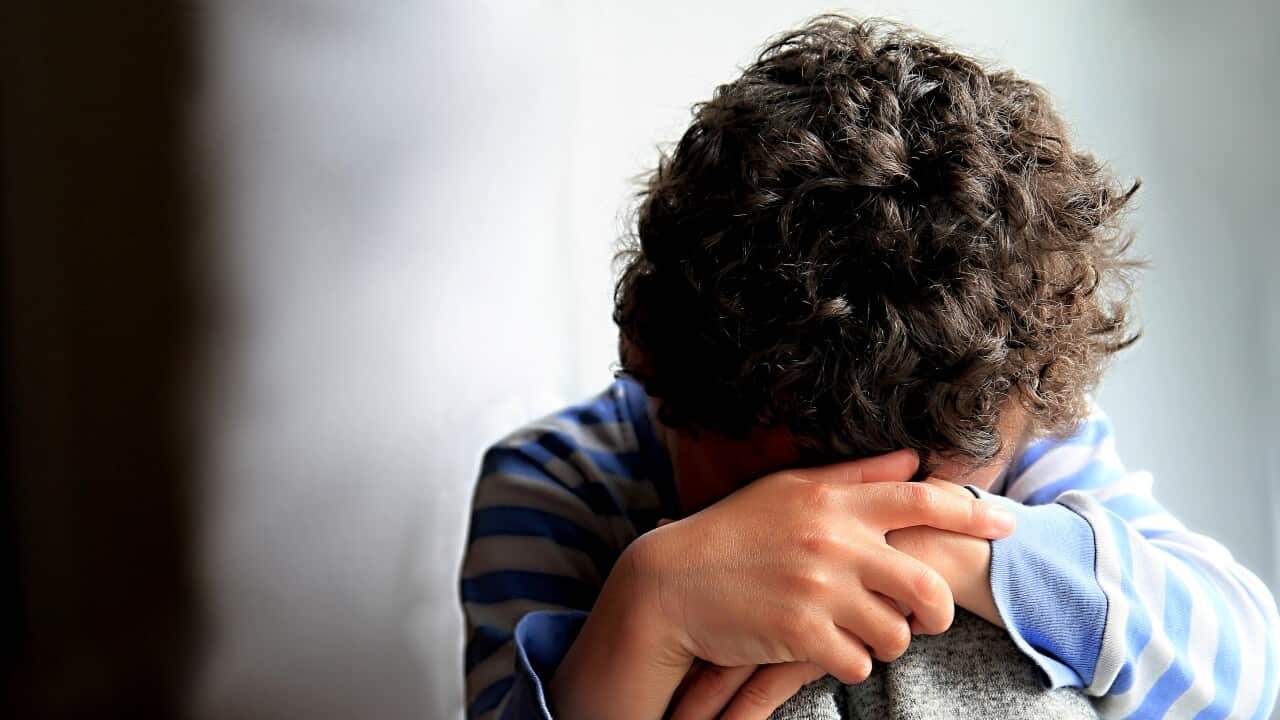 Boy Praying With Hands Over Face Against Wall At Home Stock Photo