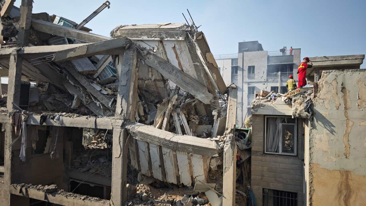 People looking through the rubble of buildings which have been badly damaged.